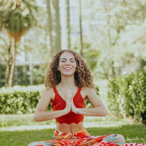 Smiling woman stretching gently on a yoga mat in nature.